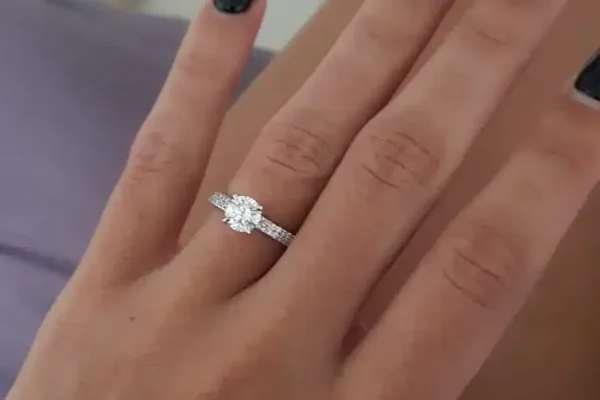 לקוחה מציגה טבעת משובצת עם יהלום עגול ושתי שורות של משובצות